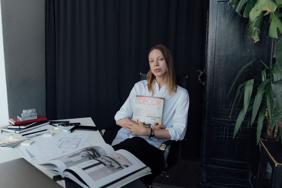 A female interior designer holding a design magazine in her modern home office workspace.