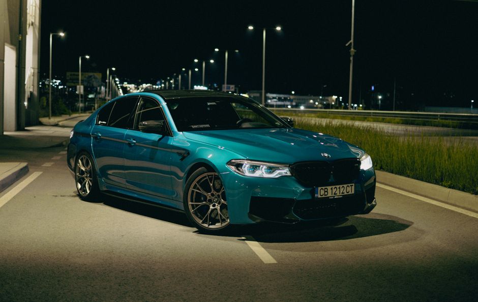 BMW M5 parked on a quiet city street, beautifully lit against the urban night backdrop.